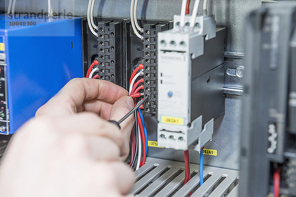 Close-up of electrician screwing cable in distribution fusebox  Munich  Bavaria  Germany
