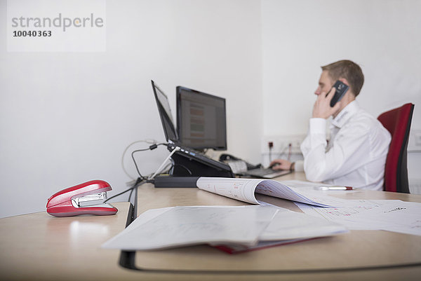 Man working in office and talking on mobile phone  Munich  Bavaria  Germany