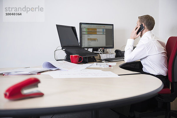 Man working in office and talking on mobile phone  Munich  Bavaria  Germany