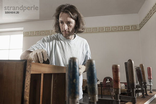 Carpenter French polishing wooden drawer at workshop  Bavaria  Germany