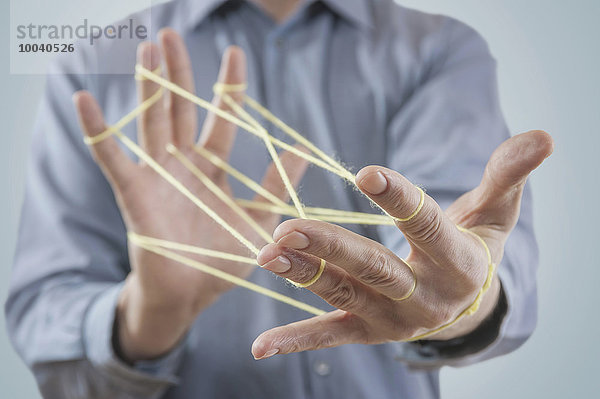 Mid section view of a man's hands making a cats cradle with string  Bavaria  Germany