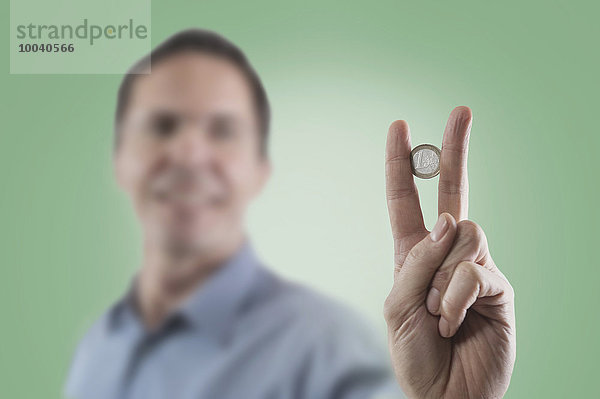 Businessman holding one euro coin between two fingers  Bavaria  Germany