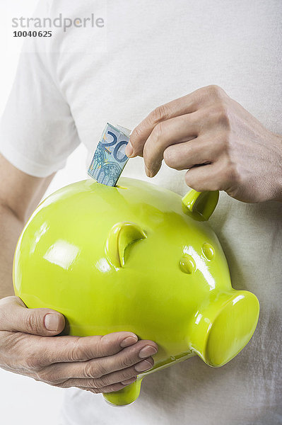 Man putting banknote into a piggy bank  Bavaria  Germany