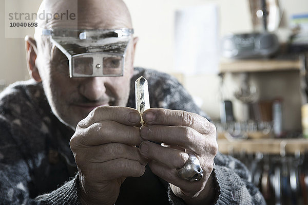 Senior male goldsmith looking at crystal  Bavaria  Germany