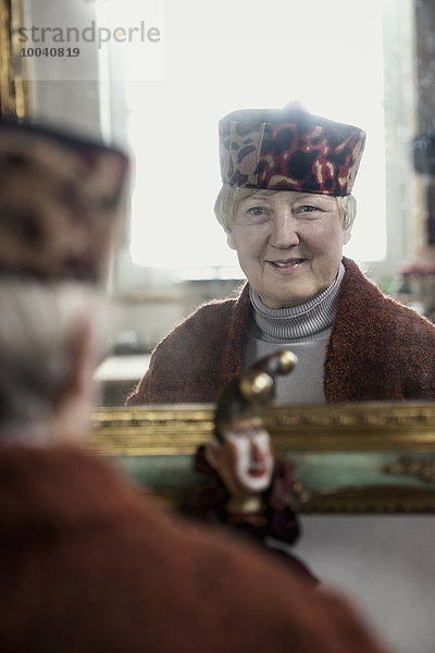 Portrait of senior female fashion designer checking cap in mirror  Bavaria  Germany
