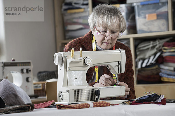 Senior female fashion designer stitching in workshop  Bavaria  Germany