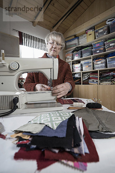 Senior female fashion designer stitching in workshop  Bavaria  Germany