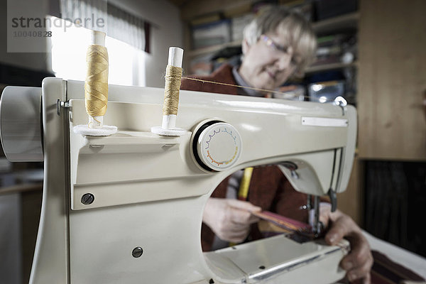 Senior female fashion designer stitching in workshop  Bavaria  Germany