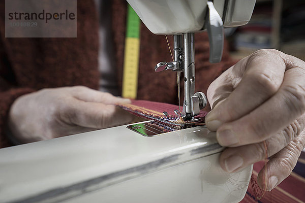 Senior female fashion designer stitching in workshop  Bavaria  Germany
