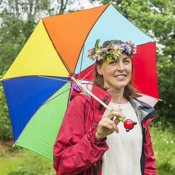 Frau Blume lächeln Regenschirm Schirm halten Blumenkranz Kranz