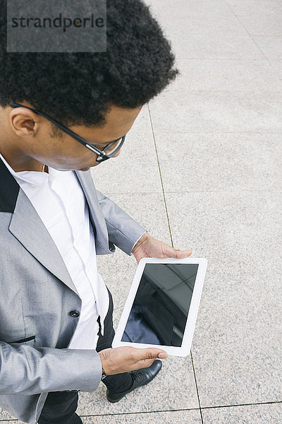 Junger Mann mit einem digitalen Tablett im Freien