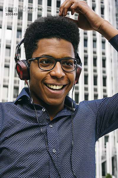 Lächelnder junger Mann mit Kopfhörer im Freien