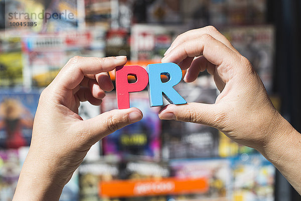 Word-PR vor dem Kiosk zum Verkauf von Zeitungen und Zeitschriften  Hände mit Holzbuchstaben