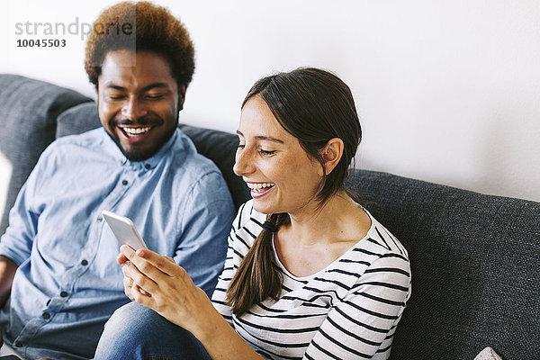 Junges Paar auf der Couch sitzend  mit Laptop und Smartphone