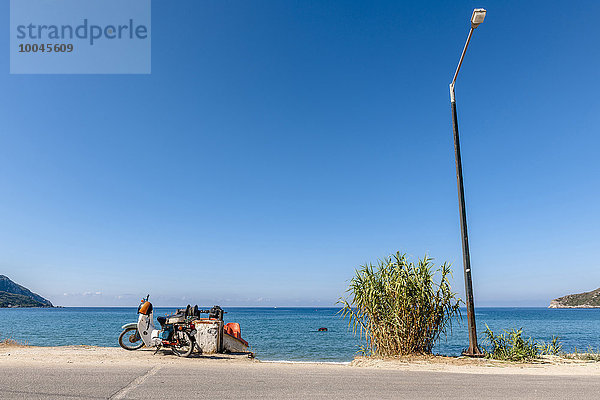 Griechenland  Korfu  Agios Georgios  Moped und Straßenlaterne am Meer