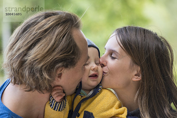 Vater und Mutter küssen ihren kleinen Sohn.