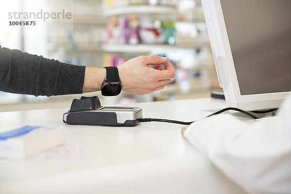 Kunde bezahlt bargeldlos mit smartwatch in der Apotheke