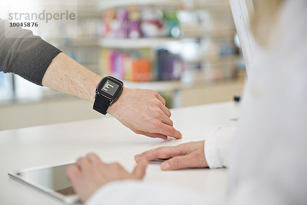 Kunde zeigt Apothekerin seine smartwatch