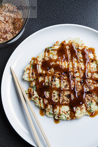 Teller mit Okonomiyake und Essstäbchen