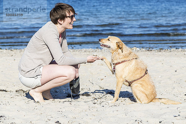 Deutschland  Kiel  Frau mit Hund am Sandstrand