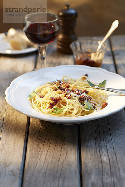 Spaghetti mit Tomatenpesto und geriebenem Parmesan und einem Glas Rotwein