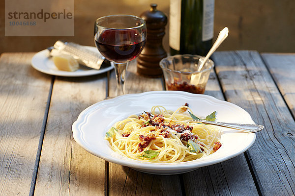 Spaghetti mit Tomatenpesto und geriebenem Parmesan und einem Glas Rotwein