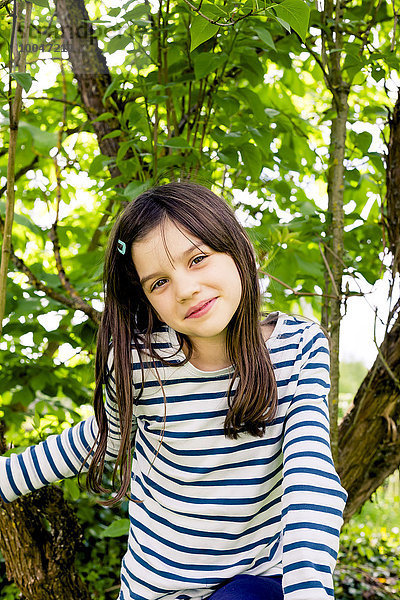 Porträt eines Mädchens beim Klettern im Baum