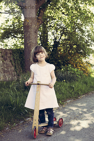 Porträt des kleinen Mädchens mit altem Holzroller