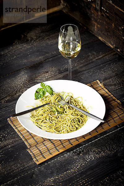 Spaghettiteller mit Pesto Genovese und einem Glas Weißwein