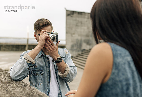 Spanien  Gijon  junger Mann beim Fotografieren seiner Freundin mit einer alten Kamera