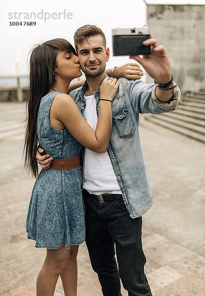 Spanien  Gijon  junges Paar  das einen Selfie mit einer alten Kamera nimmt
