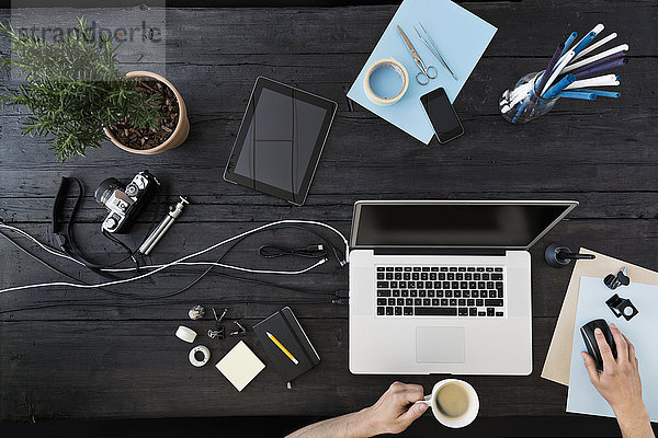 Mann arbeitet zu Hause im Büro mit Laptop beim Kaffeetrinken