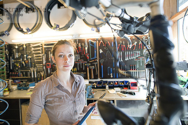 Junge Frau  die in einer Fahrradwerkstatt arbeitet