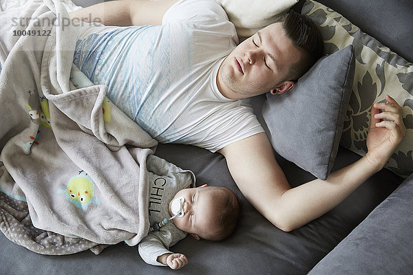 Junger Vater und Baby schlafen auf der Couch
