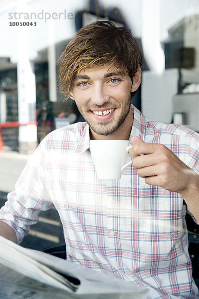 Porträt eines lächelnden jungen Mannes in einem Café