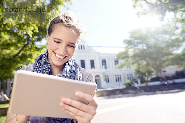 Glückliche junge Frau mit digitalem Tablett im Freien