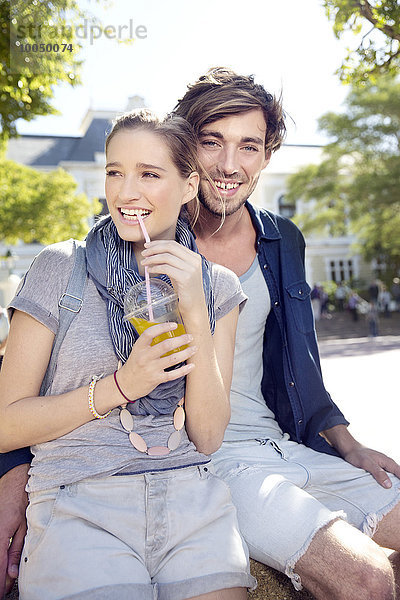 Lächelndes junges Paar im Freien mit Erfrischungsgetränk
