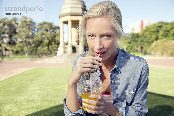 Junge Frau im Park mit Erfrischungsgetränk