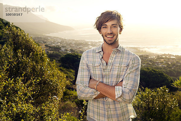 Porträt eines lächelnden jungen Mannes an der Küste