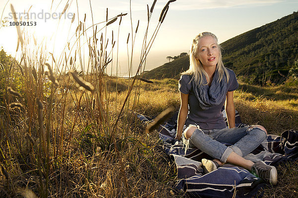Junge Frau entspannt sich auf einer Decke auf der Wiese