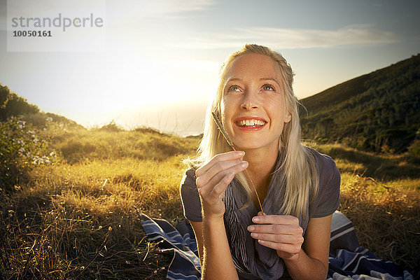 Lächelnde junge Frau in abgelegener Landschaft schaut nach oben