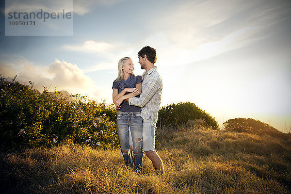 Junges Paar umarmt sich in abgelegener Landschaft