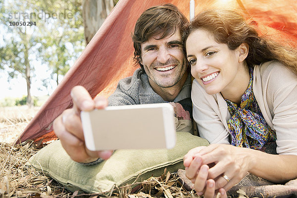 Südafrika  glückliches Paar im Zelt liegend mit einem Selfie