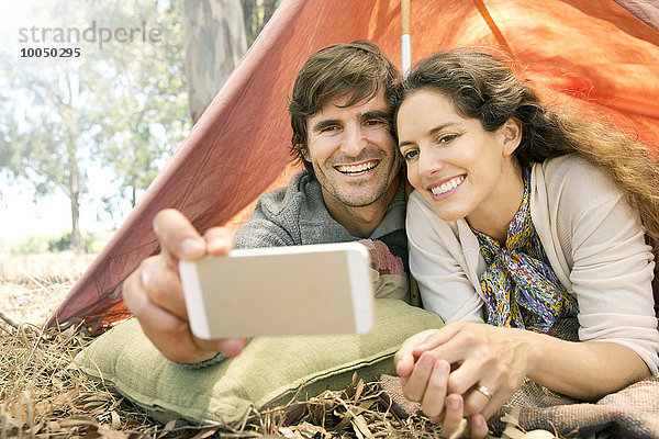 Südafrika  glückliches Paar im Zelt liegend mit einem Selfie