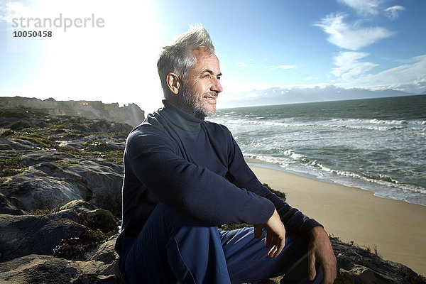 Südafrika  Porträt eines lächelnden Mannes auf Felsen am Strand