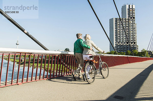 Deutschland  Mannheim  Altes Ehepaar überquert Brücke  Schiebefahrrad