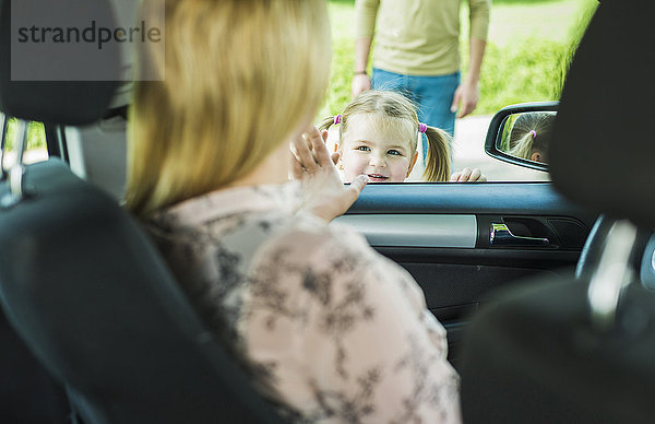 Mädchen verabschiedet sich von der Mutter im Auto