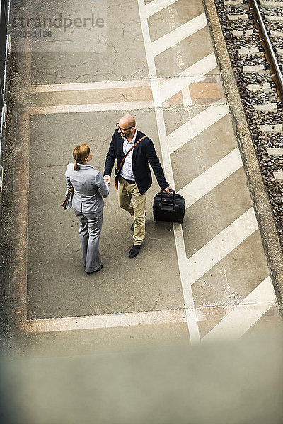 Geschäftsmann und Geschäftsfrau beim Händeschütteln auf dem Bahnsteig