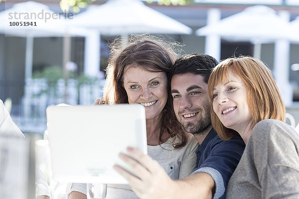 Drei Personen in einem Restaurant fotografieren mit digitalem Tablett