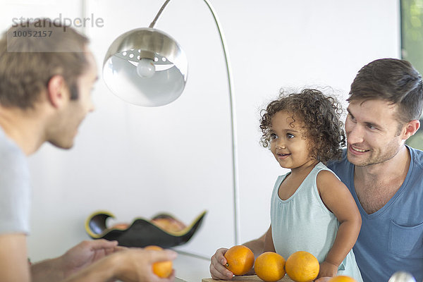 Schwules Paar mit Tochter macht Orangensaft